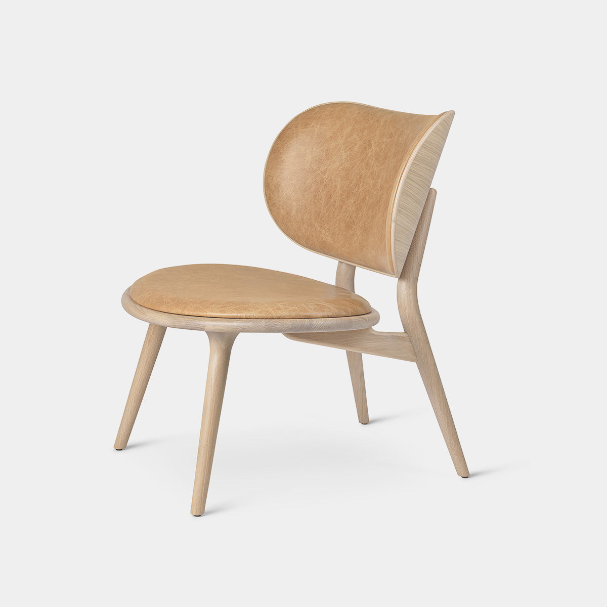 Mater Lounge Chair featuring a sculptural design with oak frame and premium leather cushions for comfort.