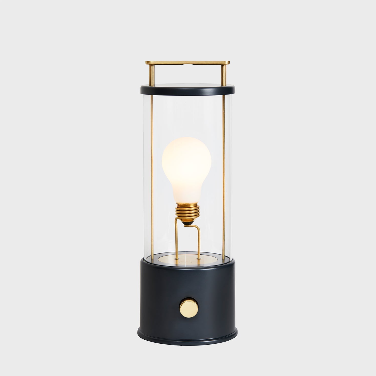 Modern black and gold lantern-style table lamp with an exposed bulb on a light grey background