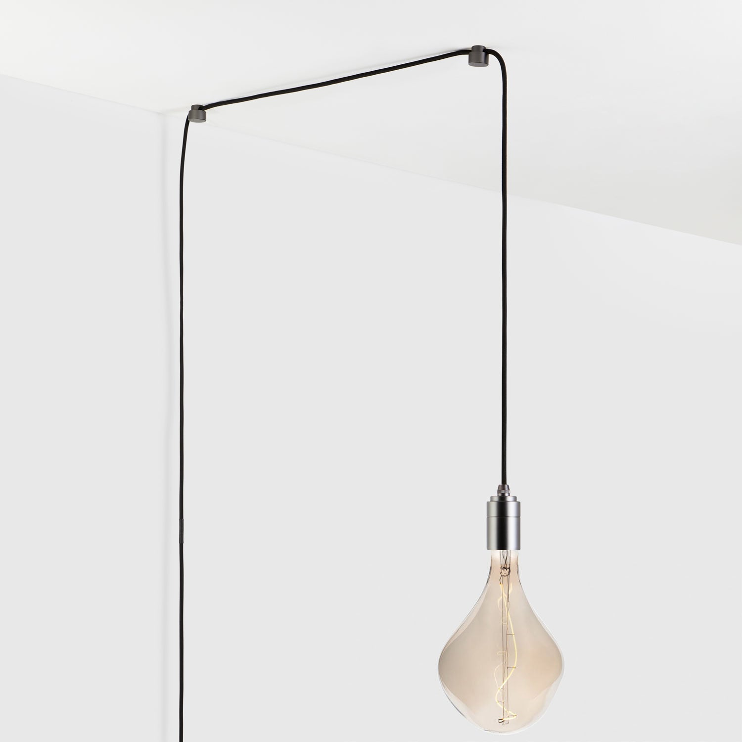 Modern minimalist pendant light hanging from ceiling with exposed bulb and black cord.