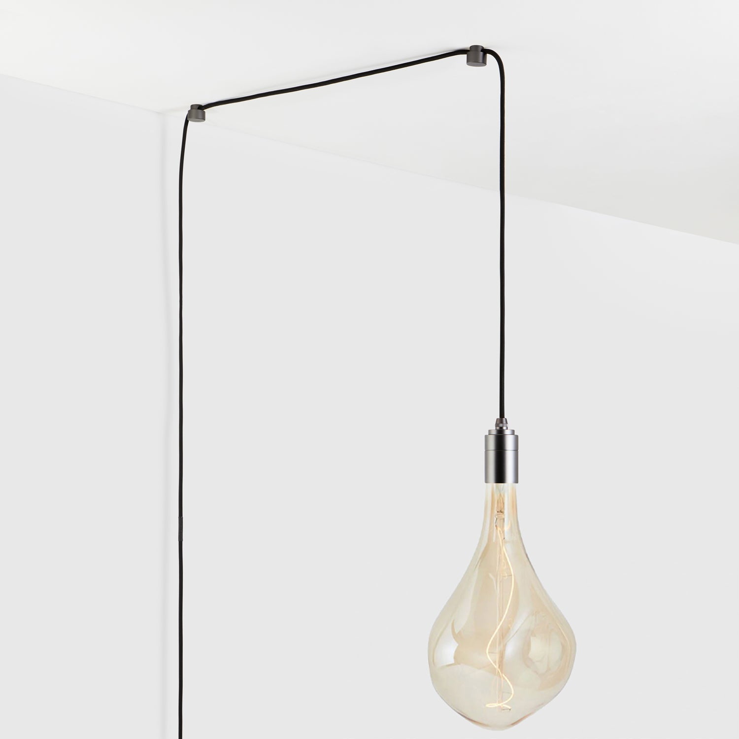 Modern hanging light bulb with exposed filament against white ceiling and wall.
