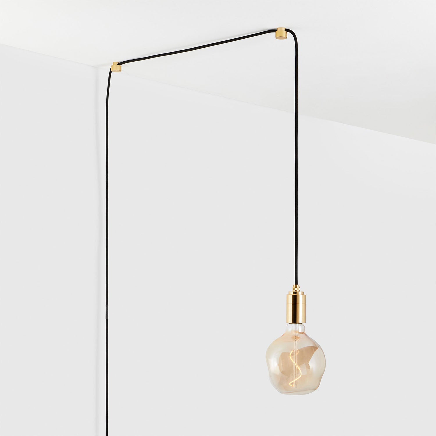 Modern hanging light bulb with minimalist design against a white ceiling and wall background