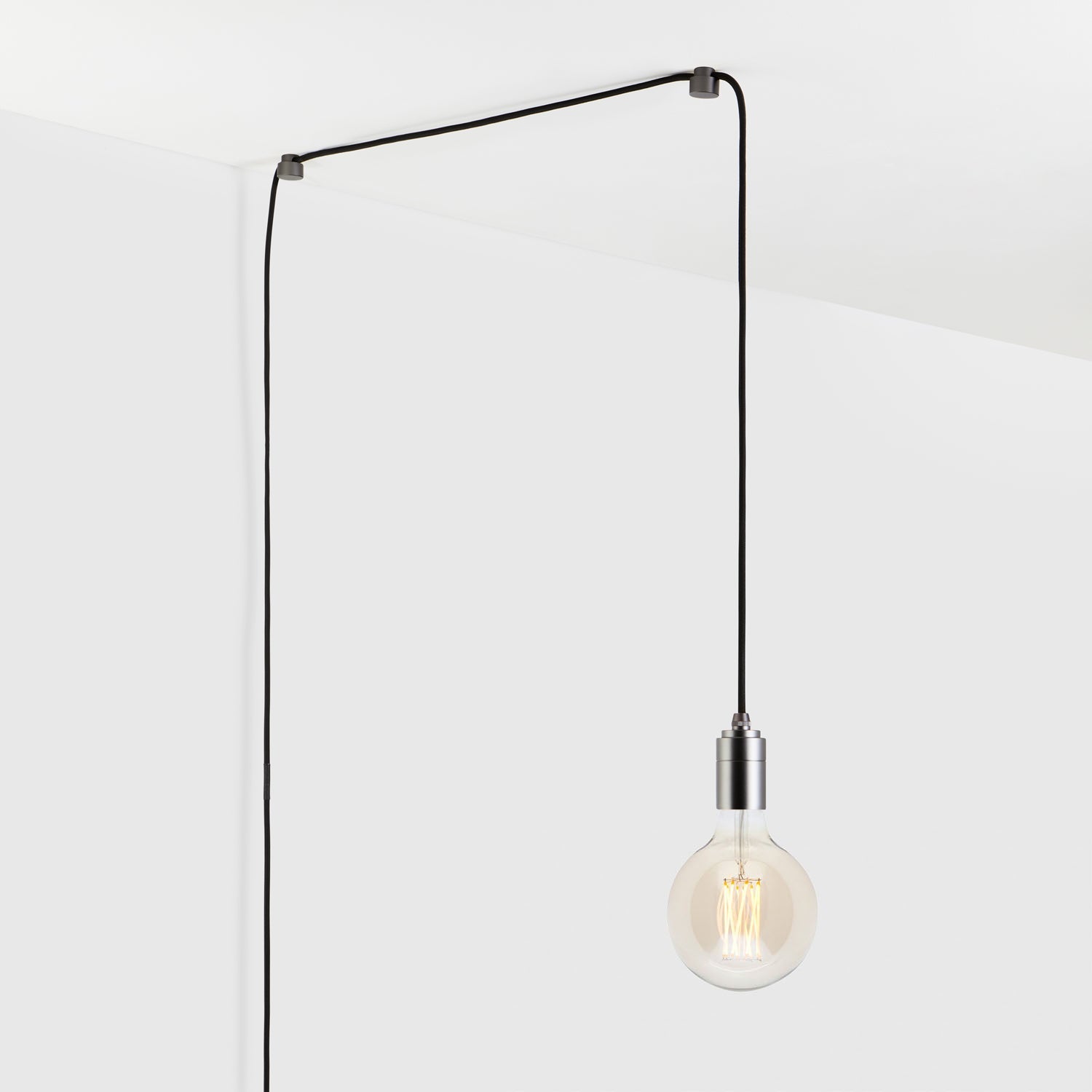 Modern hanging light bulb with black cord plugged into wall outlet