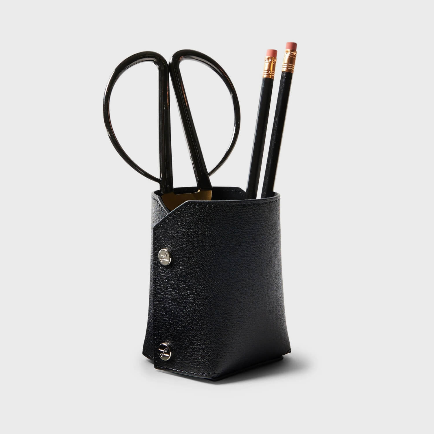 Leatherology modern pencil cup in black holding scissors and pencils, perfect for a sleek workspace on the go.