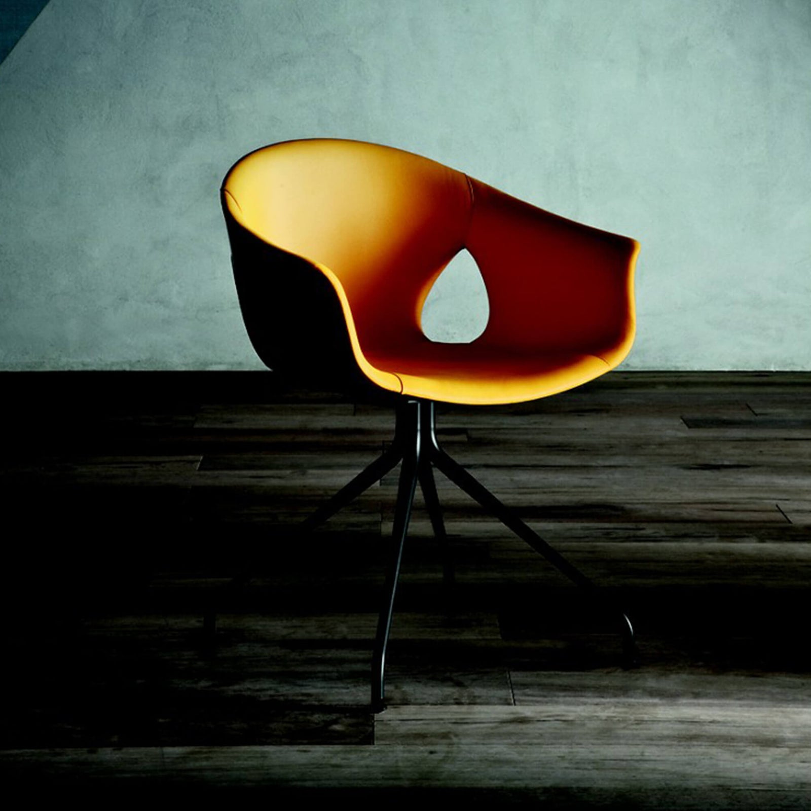 Orange-red chair with pedestal base against dark floor